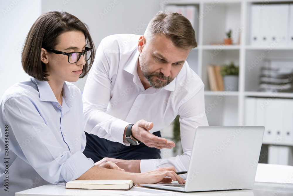 Confident economist showing online information to colleague at meeting Confident economist showing online information to colleague at meeting