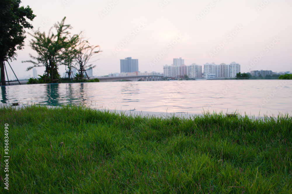 The lawn is planted beside the pool on a tall building. And near the river, with views of the city at sunset.