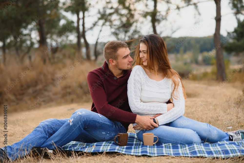 Couple in love lying on a picnic blanket in a park, enjoying beautiful autumn day in nature and cuddling Couple in love lying on a picnic blanket in a park, enjoying beautiful autumn day in nature and cuddling