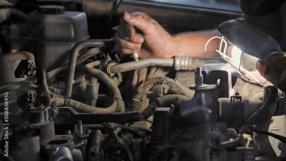 Close-up mechanic repairs the engine of the car with a lamp. 4K (UHD) Close-up mechanic repairs the engine of the car with a lamp. 4K (UHD)