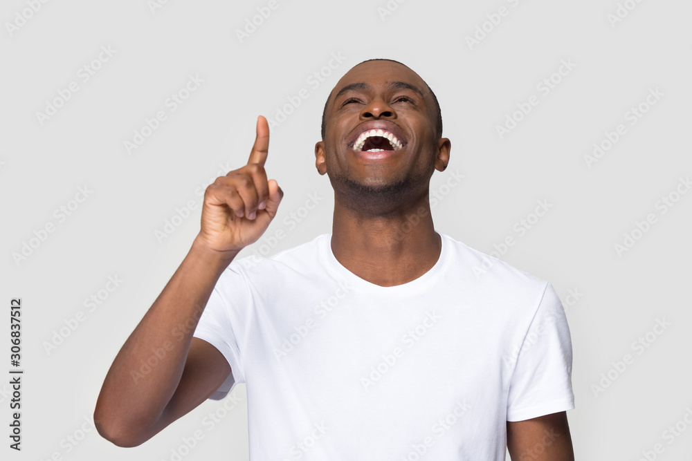 Excited laughing African American man pointing finger up