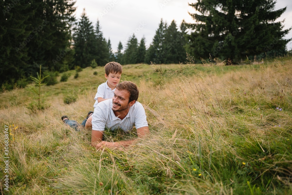 Happy father with his young son sitting on the grass on a background of ...