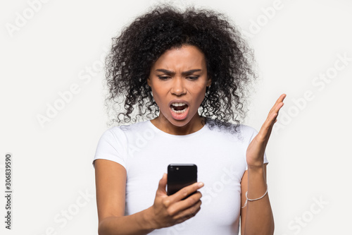 Angry African American woman looking at phone, annoyed by spam