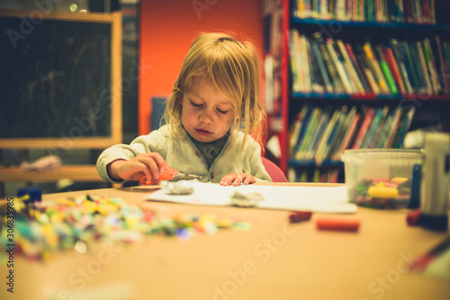 Toddler using scissors and glue at school photo