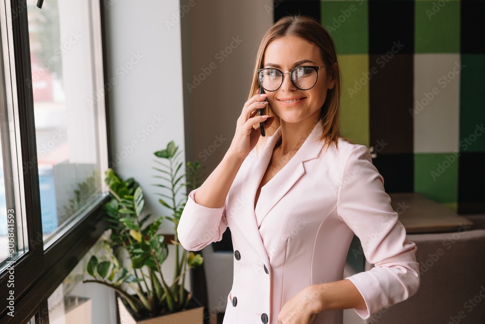 Business woman on the phone at office. Young business woman having phone call at the office. Smiling business woman. Pretty young business using smartphone at the loft office. Business woman on the phone at office. Young business woman having phone call at the office. Smiling business woman. Pretty young business using smartphone at the loft office.