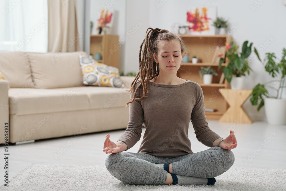 Pretty young female in activewear sitting on the floor with crossed legs Pretty young female in activewear sitting on the floor with crossed legs