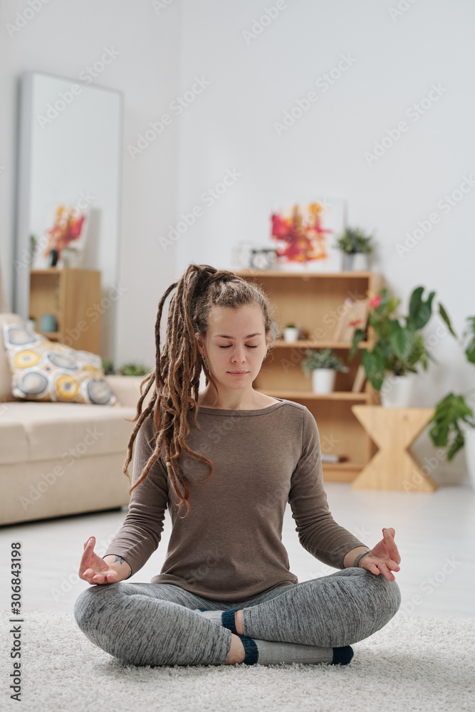 Pretty young active woman with dreadlocks sitting on the floor with crossed legs Pretty young active woman with dreadlocks sitting on the floor with crossed legs