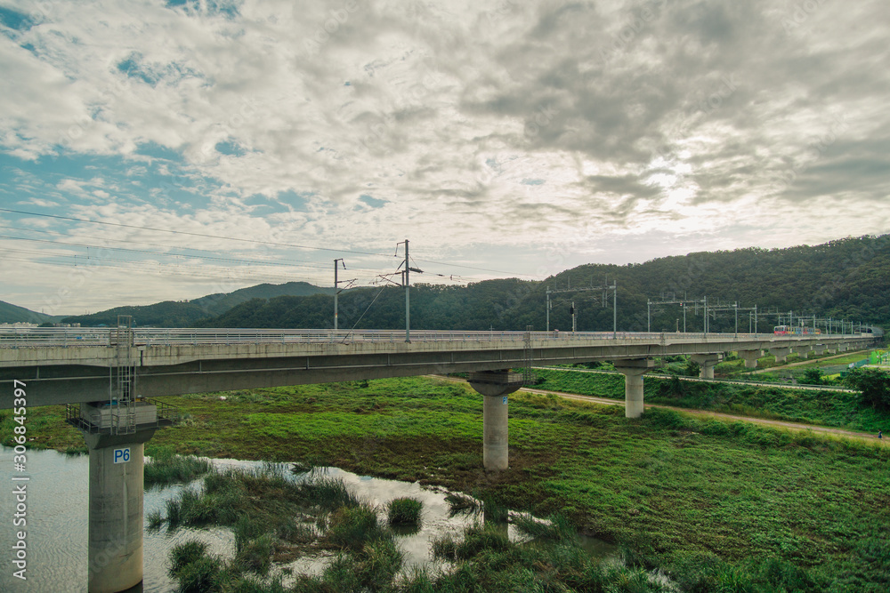 The rail road bridge above the river with cloudy sky. 