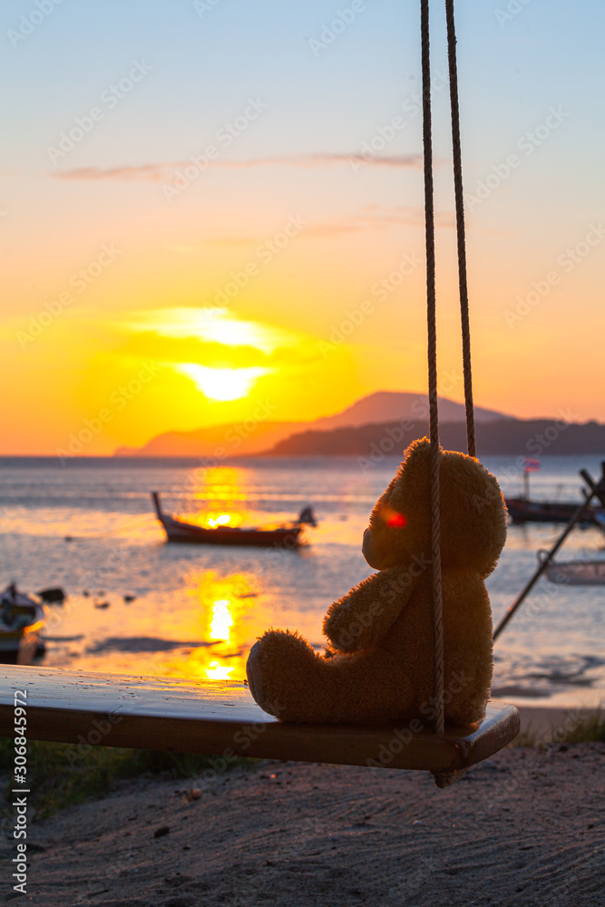 lonely Teddy Bear sitting on a swing in front Rawai beach to see sunrise.
