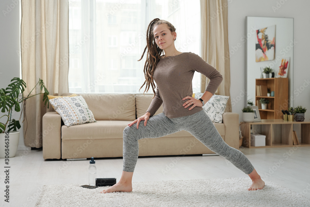 Young barefoot woman in leggings and pullover stretching legs during  exercise Stock Photo