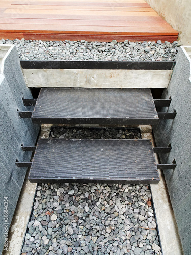 Steel stairs in with gravel and wood surface and natural wall material