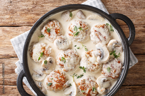 Hot meatballs with mushrooms served in creamy cheese sauce with thyme close-up in a pan. horizontal top view