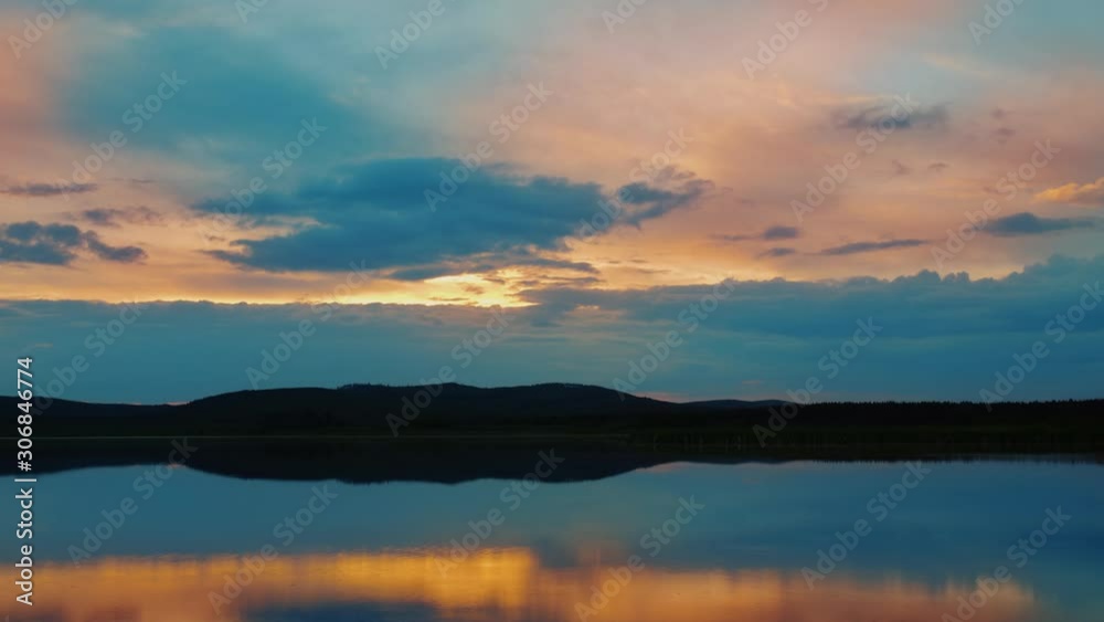 Dramatic colorful timelapse of sunset. Beautiful fiery cloudy sky moving over lake.