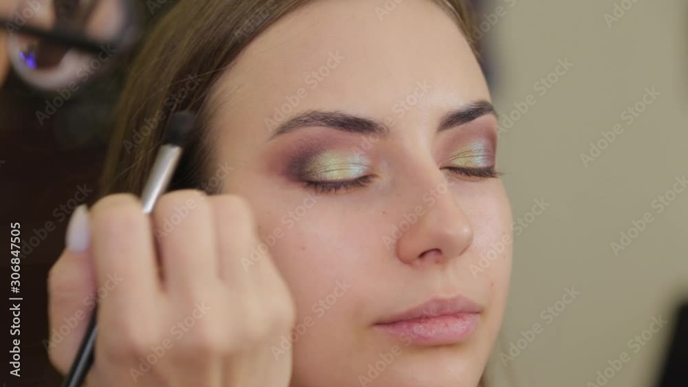Professional makeup artist puts eye shadow on a client of a beauty salon. Professional makeup artist puts eye shadow on a client of a beauty salon.