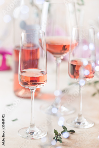 Different glasses and bottle of rose wine on light background.