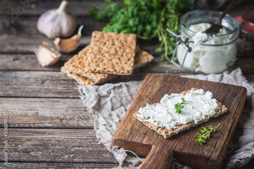 Crispbread toast with homemade herb and garlic cottage cheese on wooden background