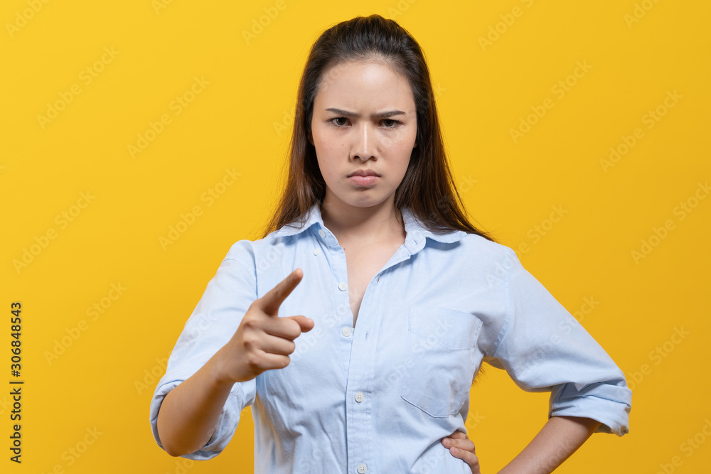 Angry asian woman feeling satisfied on the facial expression and pointing finger to camera isolated on yellow background studio shot. Angry asian woman feeling satisfied on the facial expression and pointing finger to camera isolated on yellow background studio shot.
