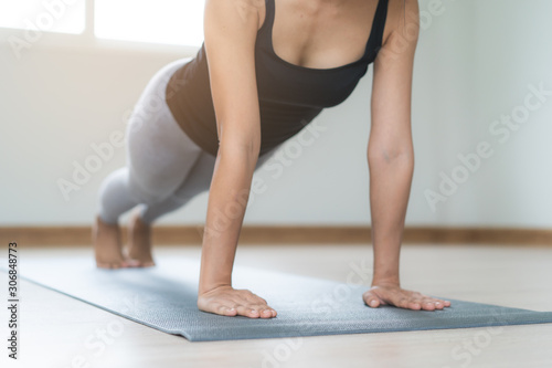 Woman exercising core body at home by doing plank pose on the yoga mat.
