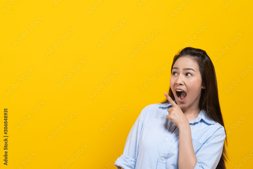 Fototapeta premium Shock asian young woman pointing finger up with surprise facial expression.