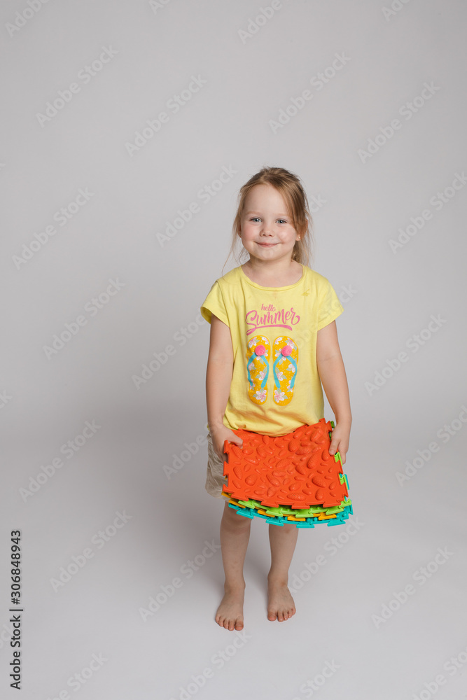 Stock photo of a child playing with colorful bright rubber pads for improving and developing fine motor skills on the floor. She is sitting on her haunches in studio. Stock photo of a child playing with colorful bright rubber pads for improving and developing fine motor skills on the floor. She is sitting on her haunches in studio.