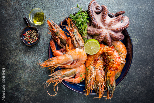Top view of big plate with grilled shrimps and octopus tentacles decorated with greenery photo