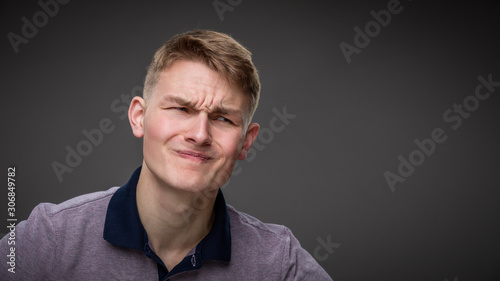 A young man grimaces in pain photo