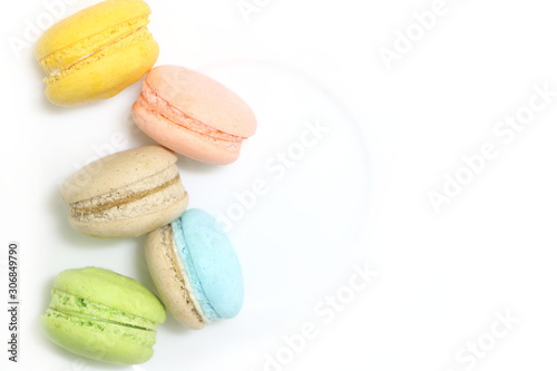 vertical line of colorful fresh sweet cake macarons on left size on white dish background, have copy space for put text.