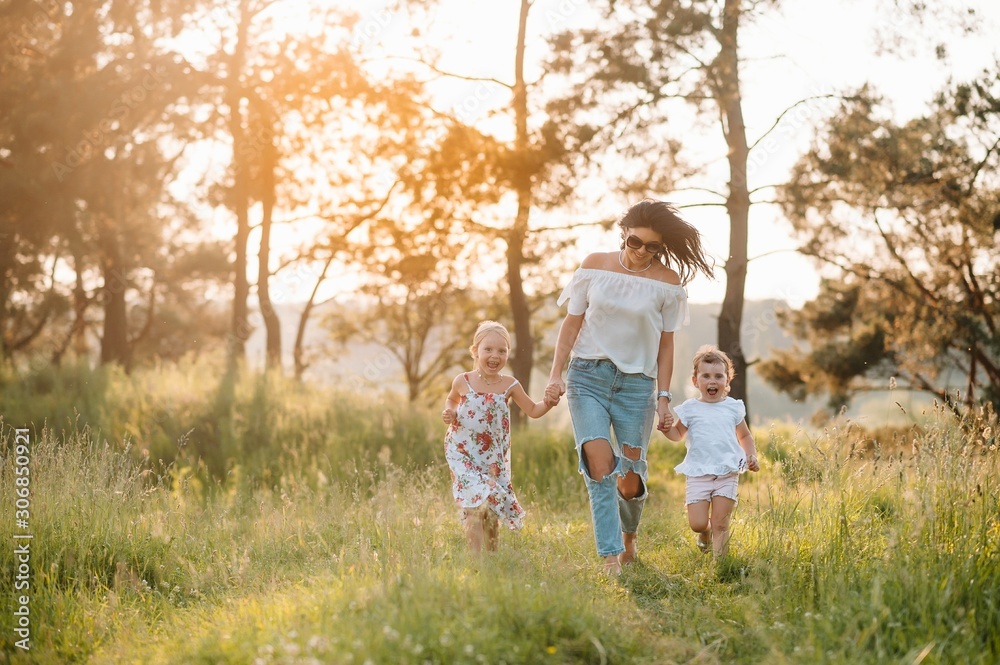 Mother and two daughters having fun in the park. Happiness and harmony in family life. Beauty nature scene with family outdoor lifestyle.