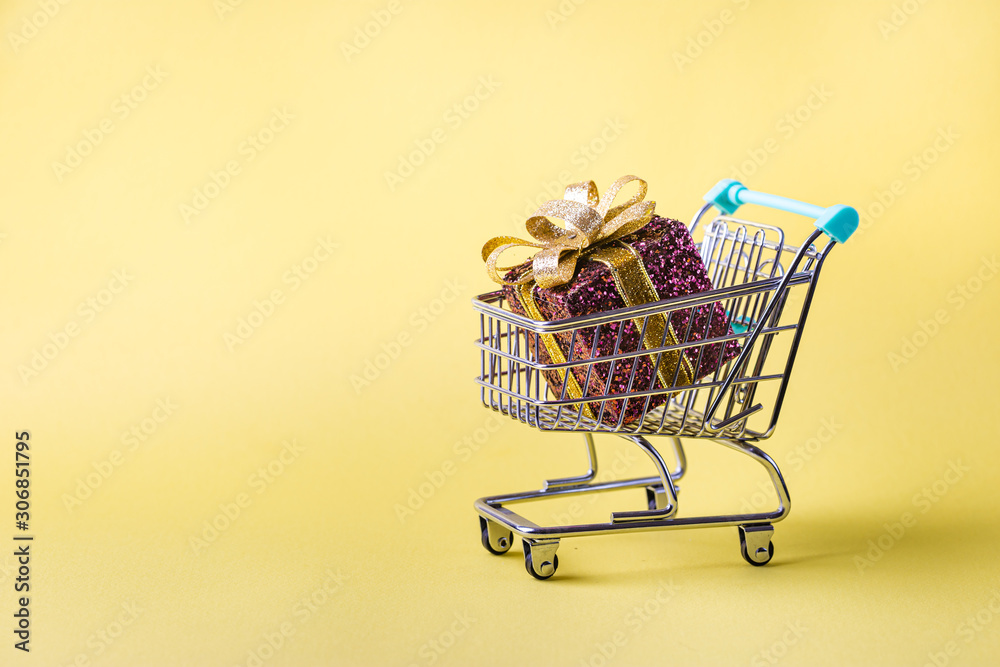 shopping cart full of christmas presents on bright yellow background