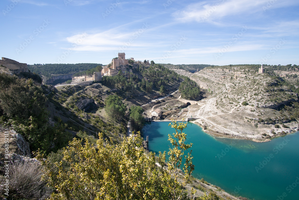 view of the medieval hillside town of Alarcon, Spain, which is located on the Jucar River. It is a popular tourist destination with the castle and guard tower pictured