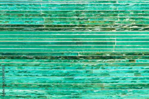 Glass background with stripe pattern in hue of green color at sunny day.