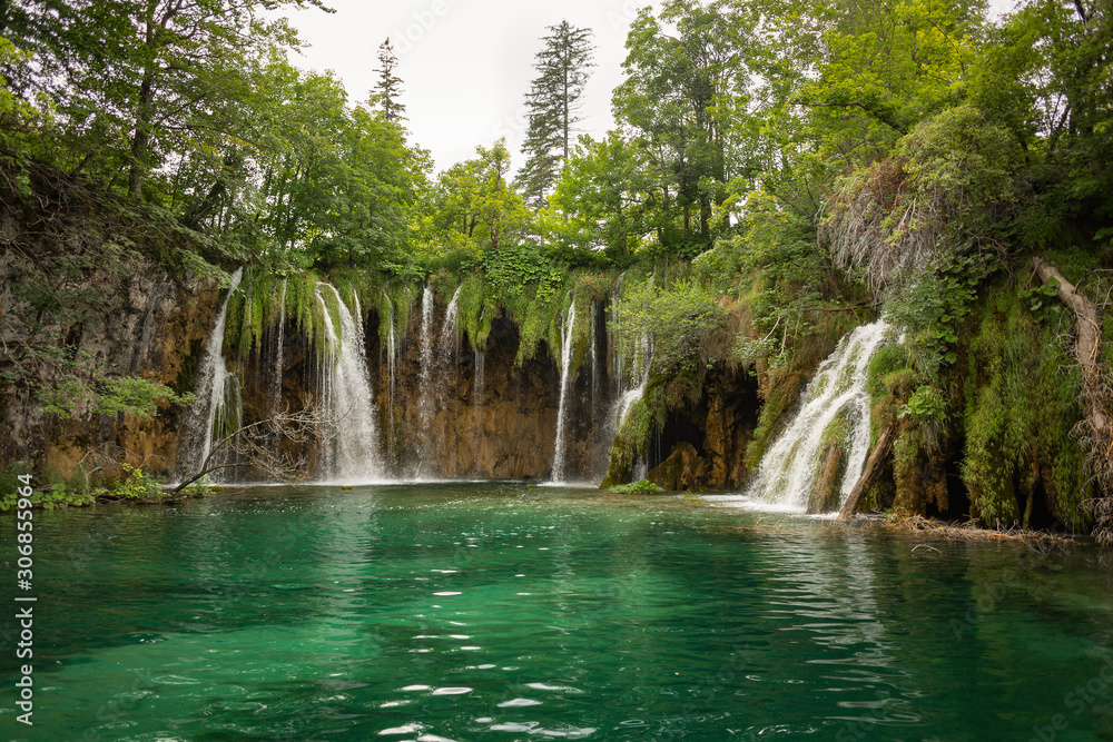 Landscape view on the waterfalls and lake in Plitvice Lakes National Park on a cloudy summer day. Waterscape, nature background. Croatia.