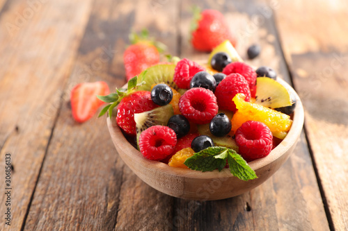 Tableau sur toile bowl of fruit salad with berry, orange, kiwi and mint