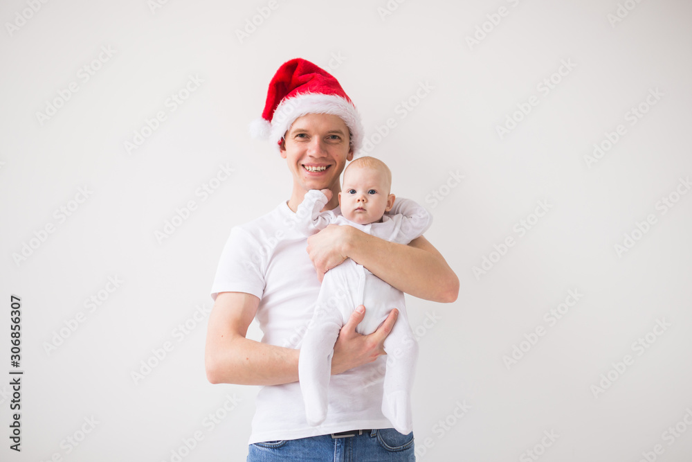 My first Christmas. Dad in santa hat holding his baby girl daughter on white background with copyspace My first Christmas. Dad in santa hat holding his baby girl daughter on white background with copyspace
