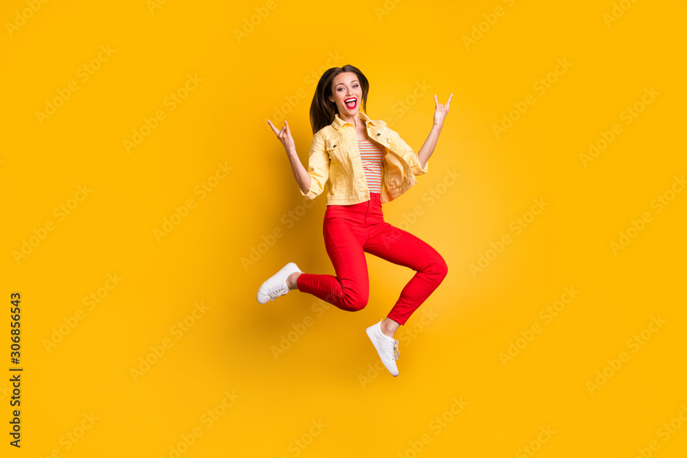 Full length body size turned photo of cheerful shouting woman showing horned fingers rock sign in red pants wearing white shoes isolated vivid color background Full length body size turned photo of cheerful shouting woman showing horned fingers rock sign in red pants wearing white shoes isolated vivid color background