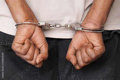 Fototapet Close-up arrested hands african man handcuffed