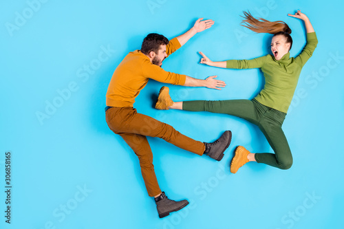 Side profile full length body size top above high angle view photo of crazy mad insane couple of karatists girl kicking man away with leg casually screaming rageously isolated pastel blue color
