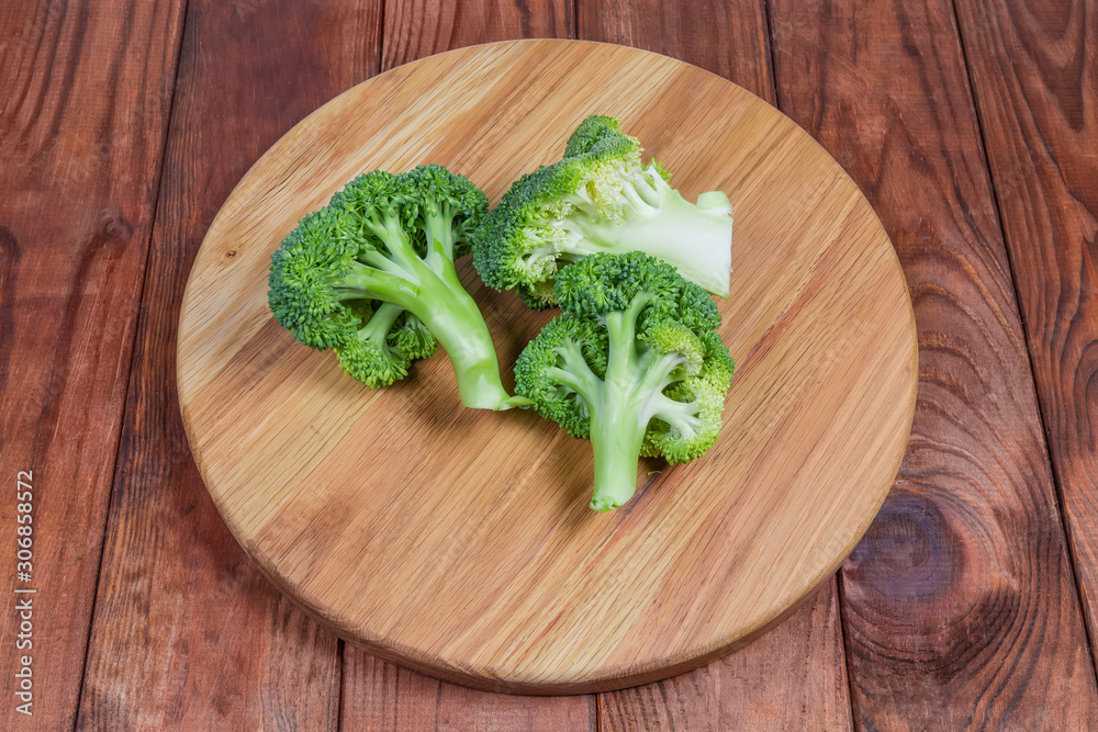 Branches of fresh raw broccoli on the wooden serving board