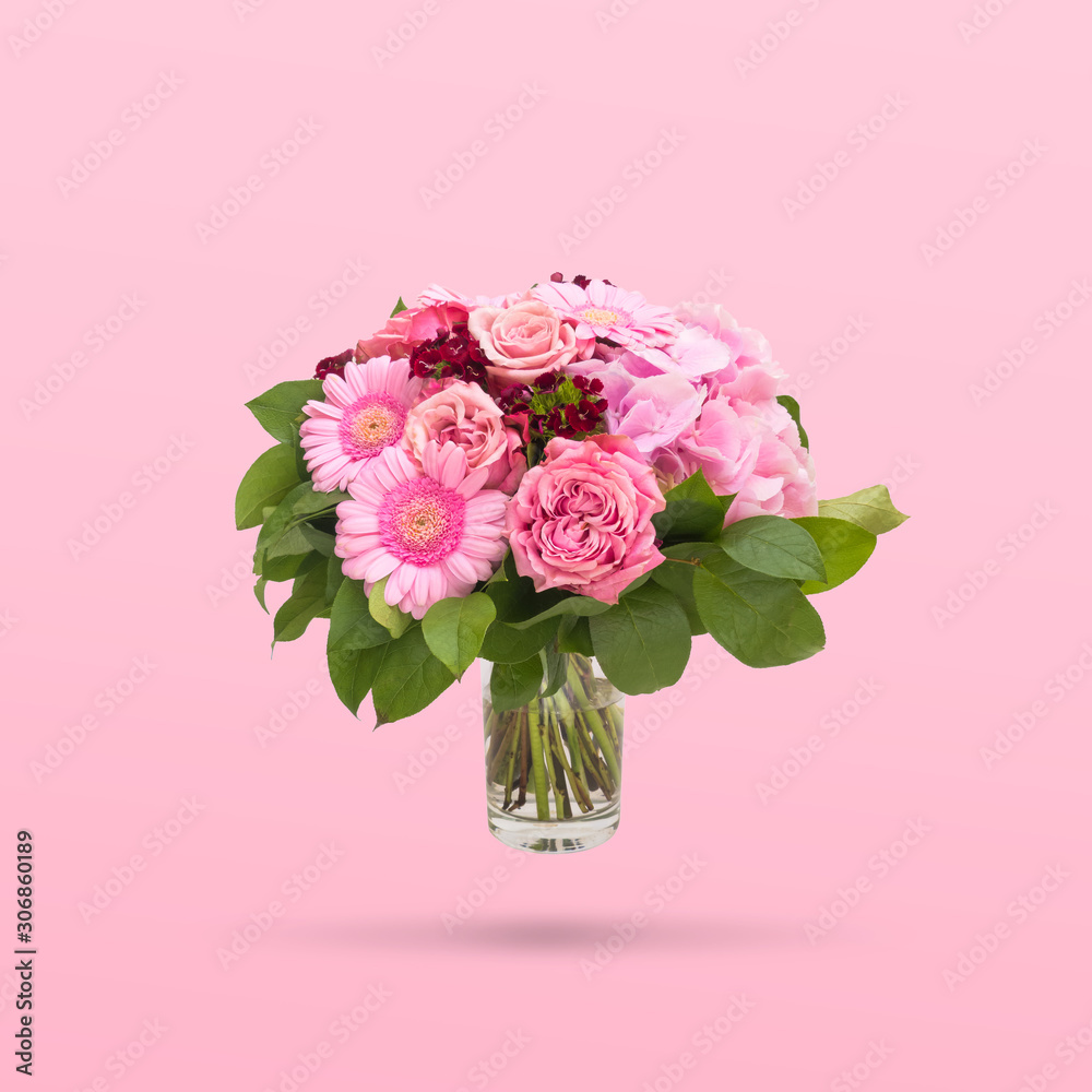Beautiful bouquet flowers in glass vase floating on pink background, minimal design
