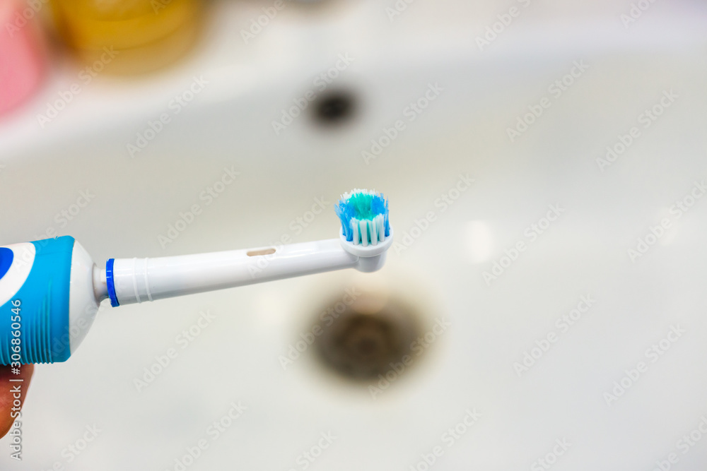 A modern electric toothbrush in white and blue colour in hand