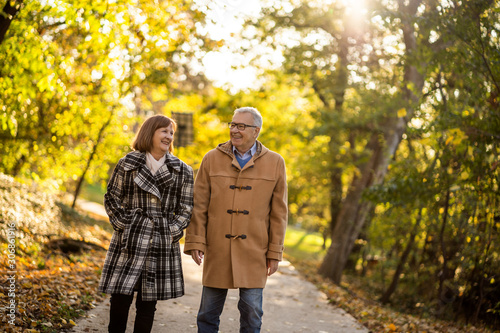 Happy senior couple is walking in park in autumn.