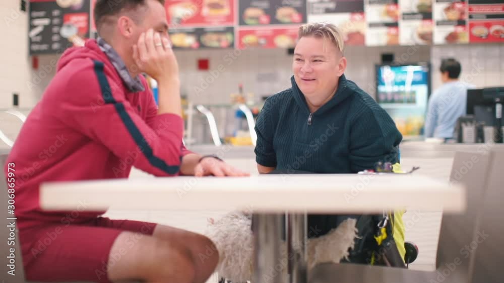The guy and his disabled wife are sitting in a restaurant at the table. The guy and his disabled wife are sitting in a restaurant at the table.