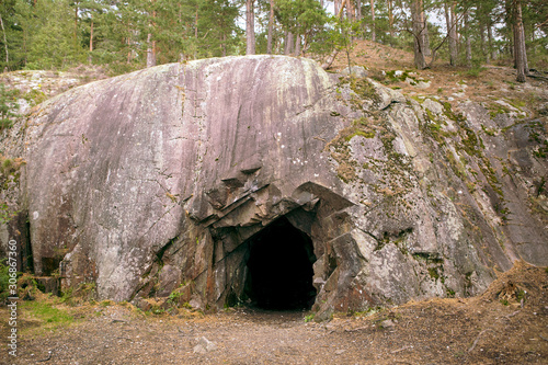 Rock wall with a dark hole, entrance to the cave in Spro, Mineral historic mine. Nesodden Norway. Nesoddtangen peninsula.