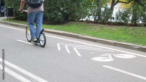 Wallpaper Mural A man on a scooter with big wheels like a bicycle rides along a bicycle path in a city park. Torontodigital.ca