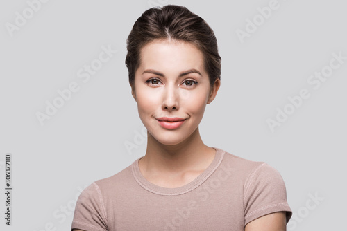 Beautiful young woman portrait. Smiling girl looking at camera isolated on gray background 