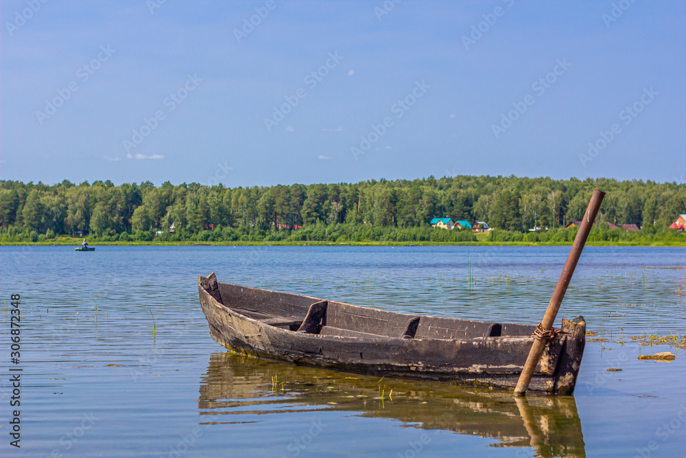 Natural landscape with moored old fishing boat on the shore of lake. Summer holiday and vacation. Fishing concept Nature background.