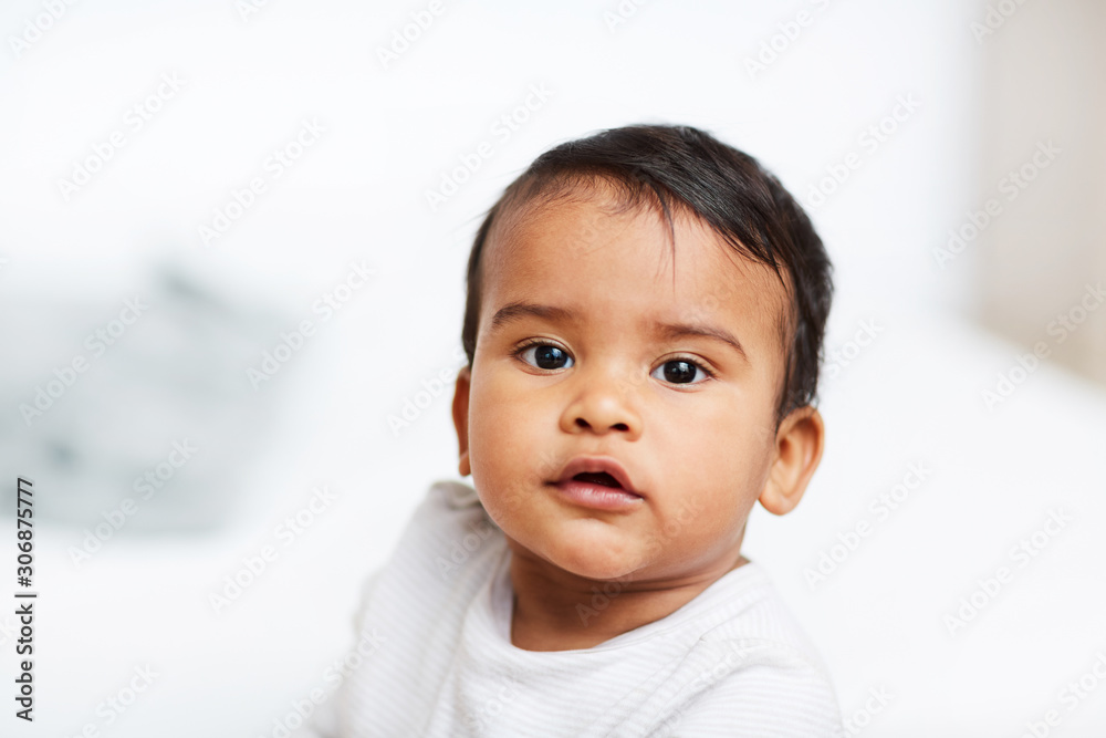 Portrait of African cute baby boy with dark hair looking at camera