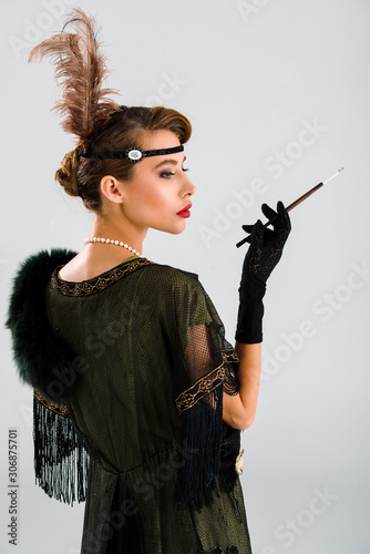 side view of elegant woman holding cigarette holder isolated on white