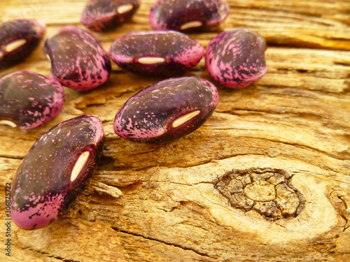 Pink and black large ripe raw beans on old wooden background. Variety of protein rich colorful fresh raw beans. Selective soft focus, close up. © Sunbunny