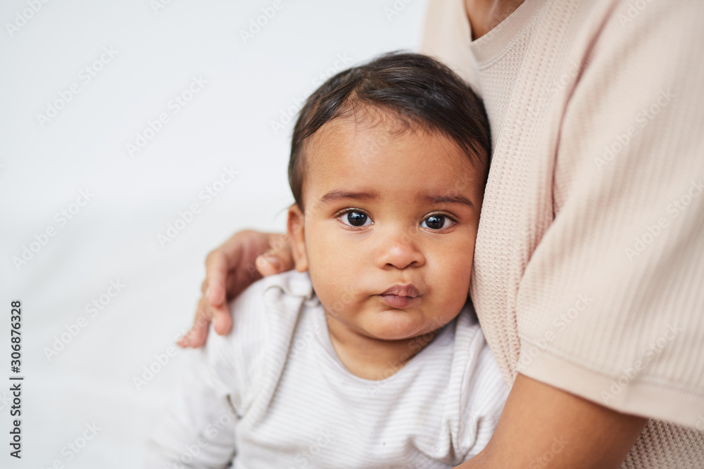 Portrait of African baby boy looking at camera while sitting on his mother's knees Portrait of African baby boy looking at camera while sitting on his mother's knees